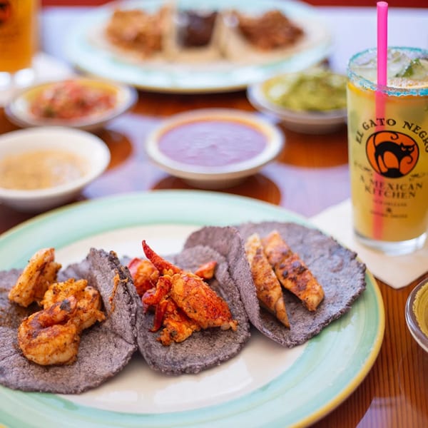 El Gato Negro's blue corn tortillas with shrimp, lobster, and chicken, alongside a branded margarita.